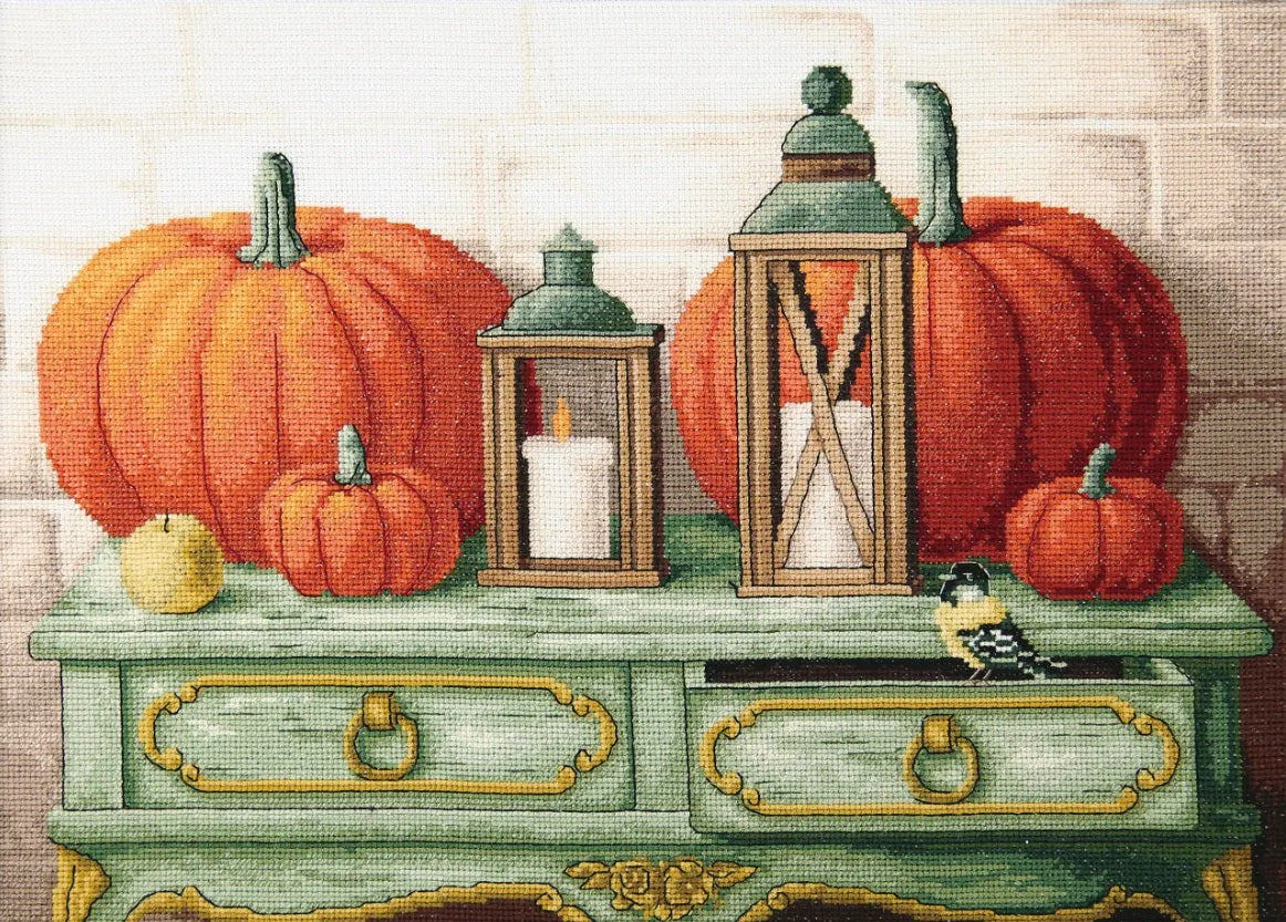 Gifts of Autumn Aida 16 Cross Stitch Kit - M-357 - Decorative scene with pumpkins, lanterns, and candles on a table against a brick wall.