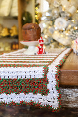 Círculo Barroco Maxcolor Sparkle – Cotton Yarn (216m / 200g) - A close-up of a handmade crocheted table runner with a white base, green and red textured stripes, and a decorative border, draped over a wooden table in a festive holiday setting.