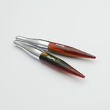 KnitPro Symfonie 2 Mini interchangeable needle tips, 5 cm - Two pointed wooden tools with silver metal collars, displayed diagonally on a clean white background. The wood features a marbled pattern of reddish-brown, dark brown, and green, with the brand name 'Ralph Lauren' printed in white script.